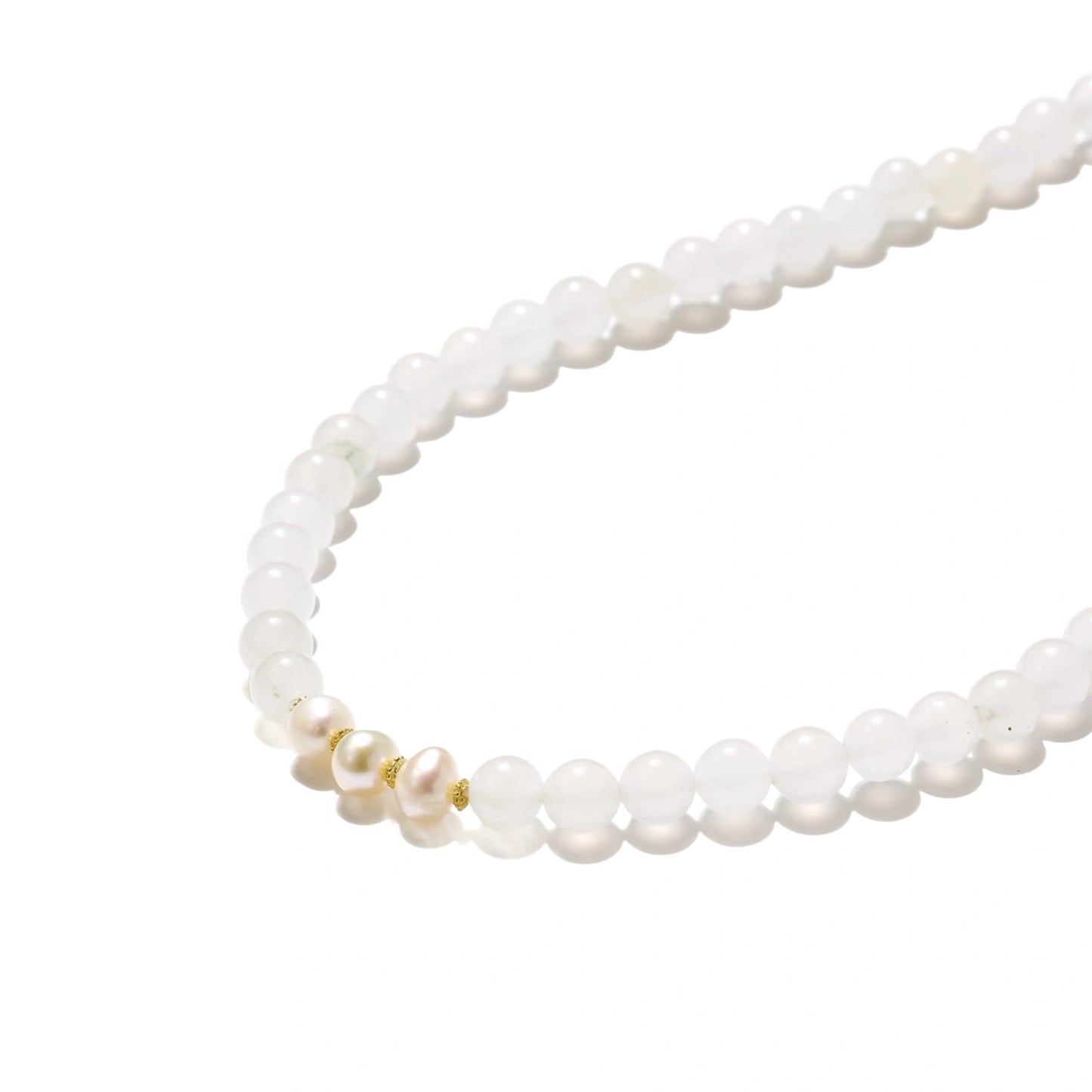 Three layered white beaded bracelets with carved orange agate lotus centerpiece and freshwater pearls on cream background.