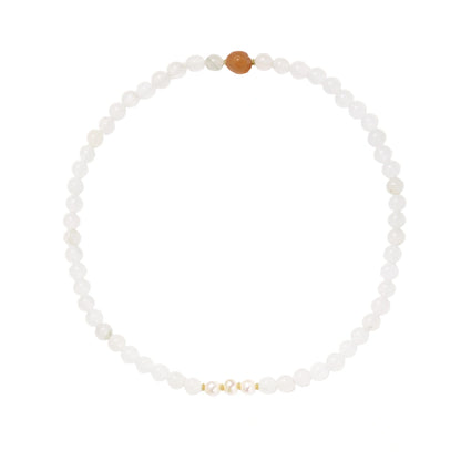 Three layered white beaded bracelets with carved orange agate lotus centerpiece and freshwater pearls on cream background.